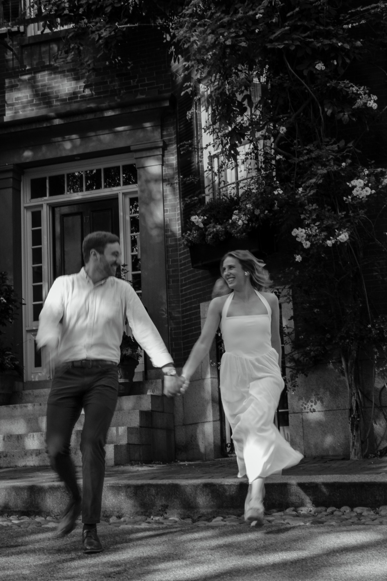 Couple running hand in hand down brownstone steps in Beacon Hill, Boston
