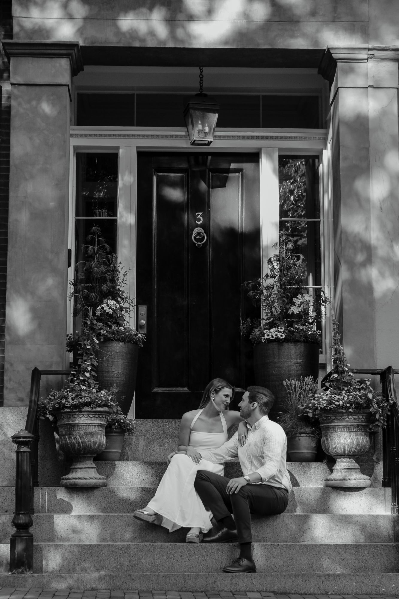 Couple sitting on front steps between flower urns in Beacon Hill, Boston