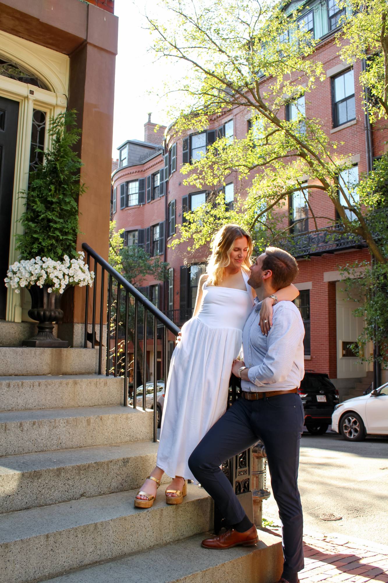 Bride-to-be in a white dress on brownstone steps with her fiancé in Beacon Hill, Boston