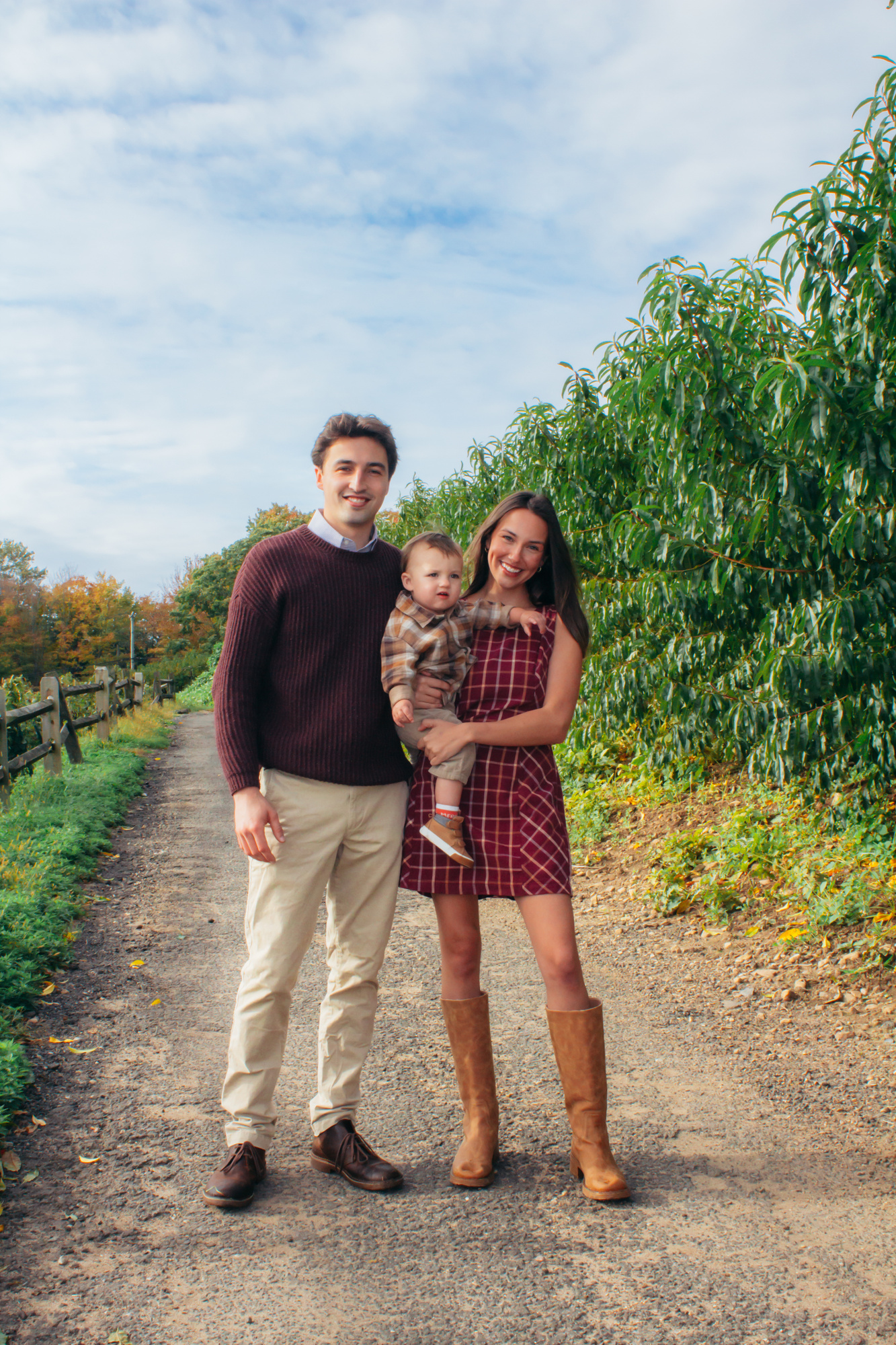 Family of three standing on a farm road beside a wooden fence at Silverman's Farm in Easton, Connecticut