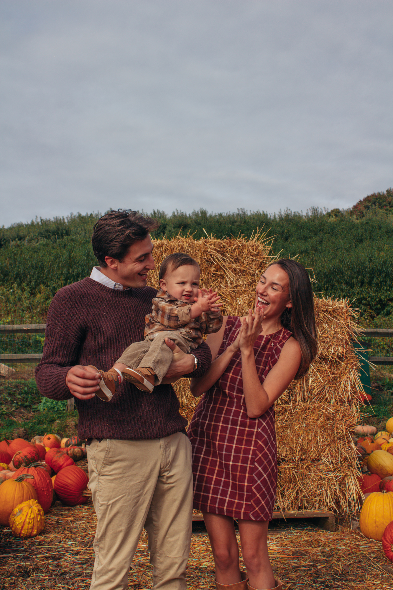Parents laughing with their son beside hay bales and pumpkins at Silverman's Farm in Easton, Connecticut