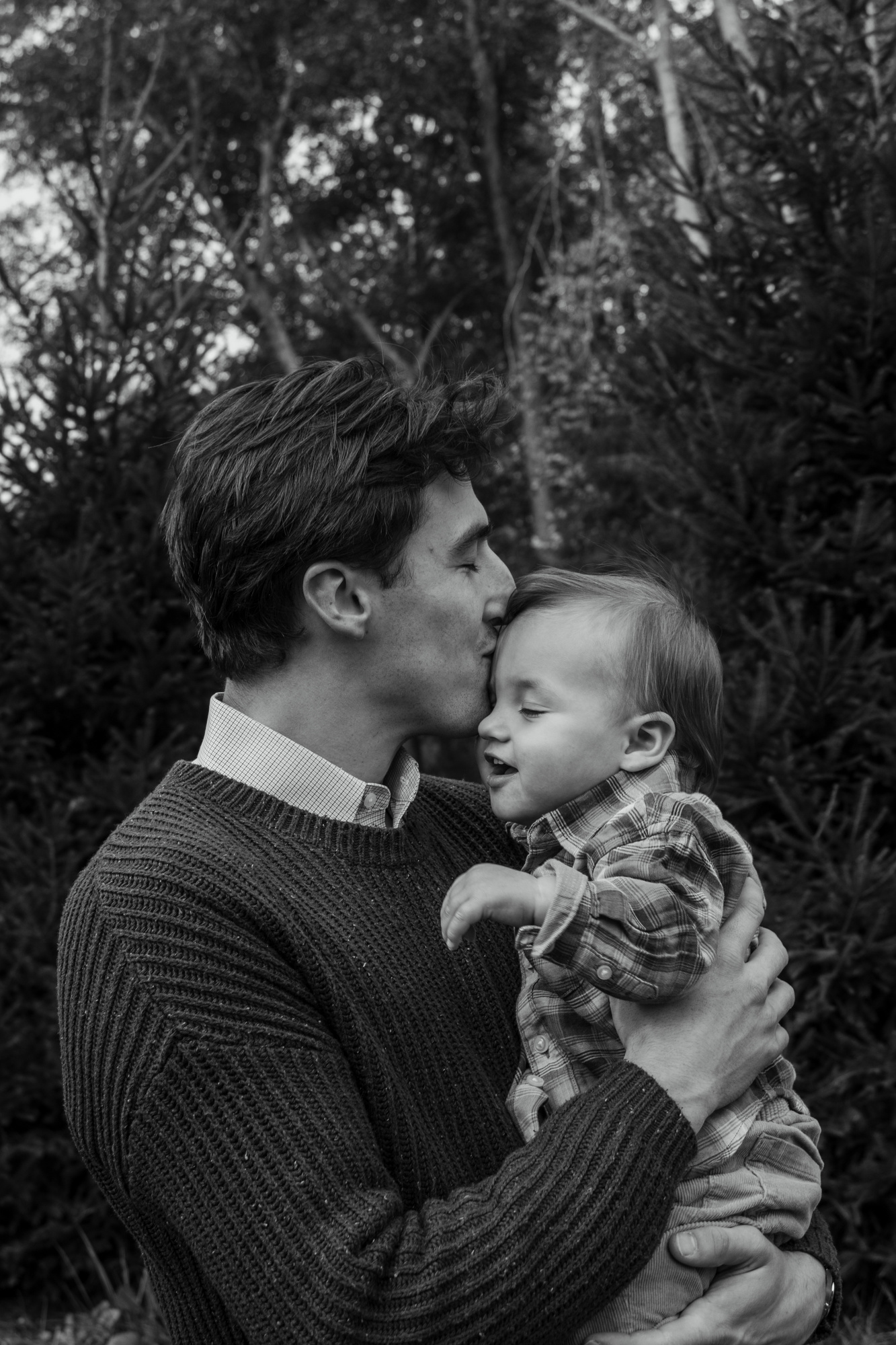 Black-and-white photo of a father kissing his smiling son's head at Silverman's Farm in Easton, Connecticut